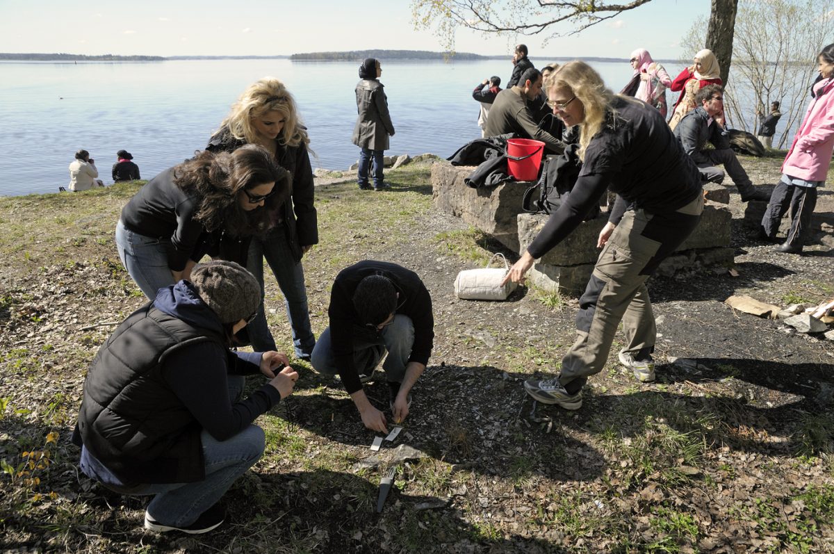 Elever lär sig att använda tändstål vid en grillplats vid sjön.