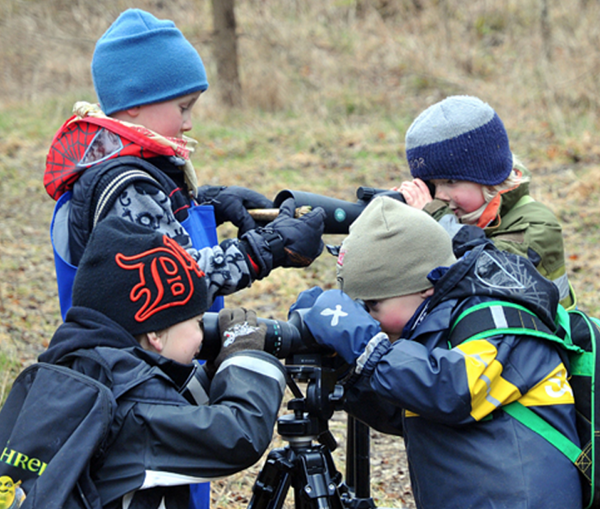 Fyra förskolebarn tittar i kikare.