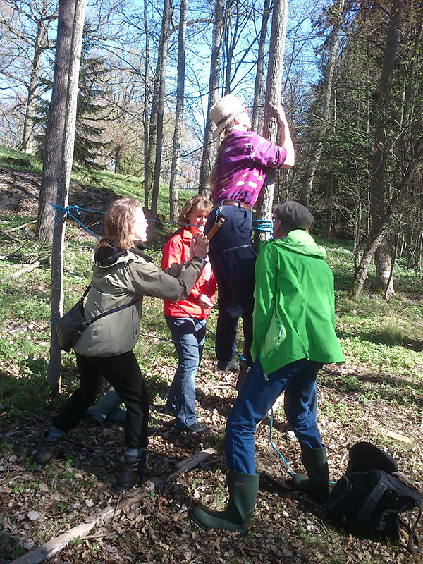 Teambuildning med Ekoturen. Tre personer hjälper en fjärde att klättra upp i ett träd